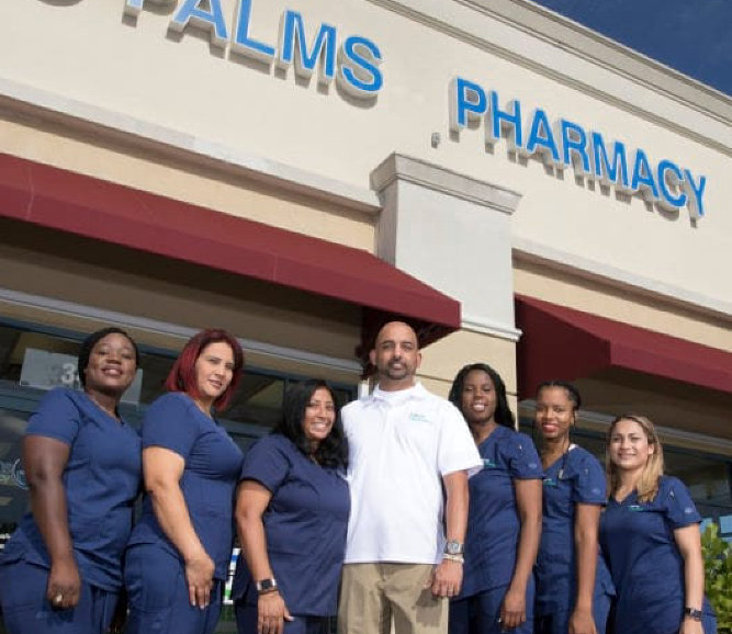 pharmacists and their owner in white standing in front of their pharmacy